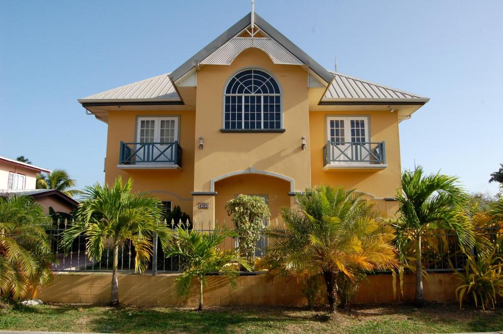 a yellow house with palm trees in front of it at Casa del Sol Tobago in Bon Accord Village