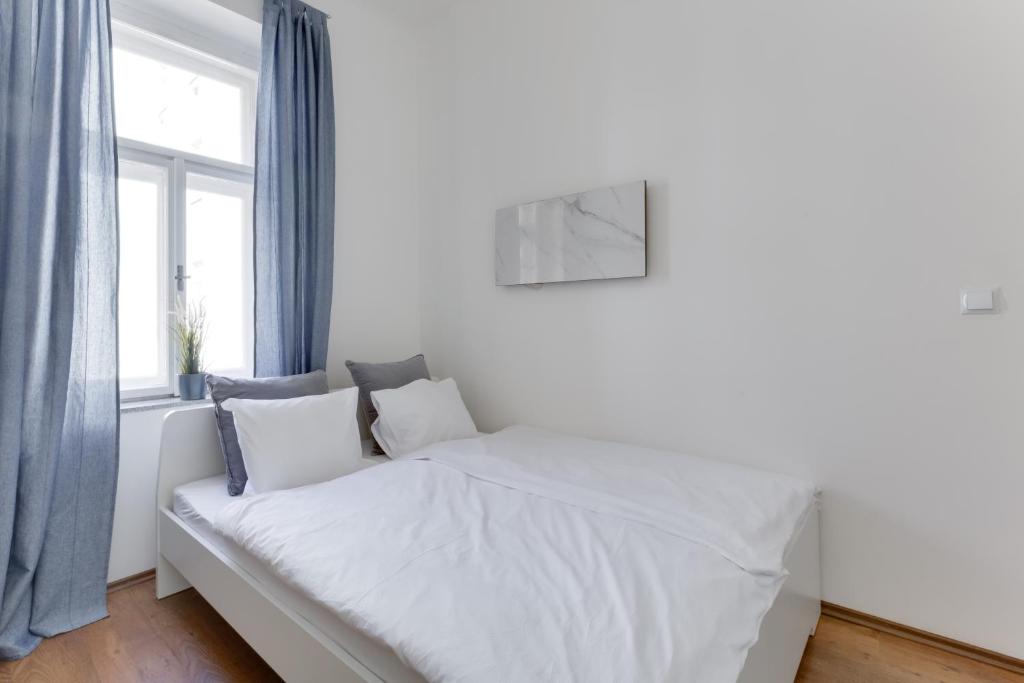 a white bed in a room with a window at JT's Apartments Benátská str. in Prague