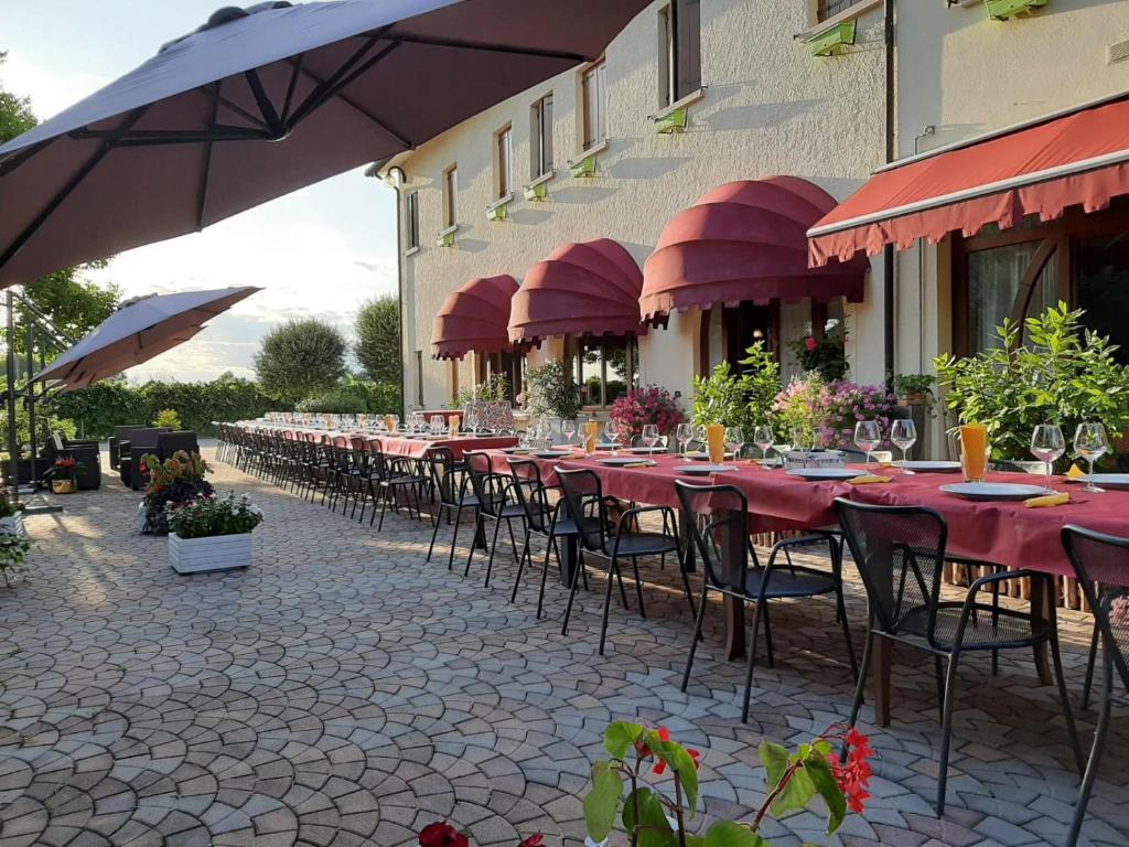 a long row of tables and chairs with red umbrellas at ca vittoria in Busco