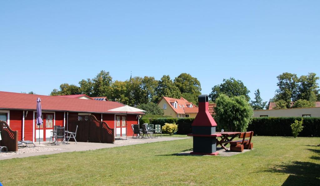 a red building with a grill in the grass at Blockhäuser an der Müritz in Ludorf