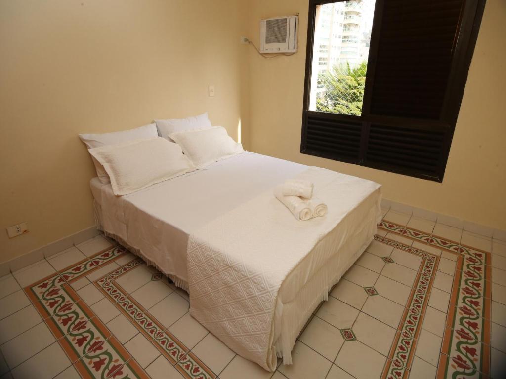 a bedroom with a bed with a towel on it at Suites Natalia Enseada in Guarujá