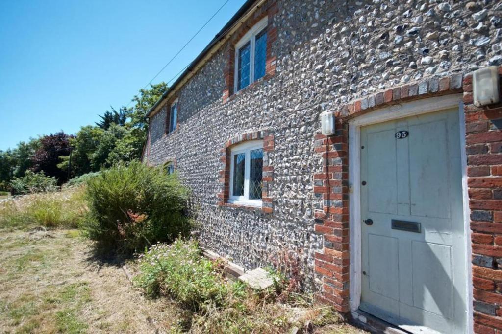um edifício de tijolos com uma porta ao lado em Wish Cottage em Ratton Village