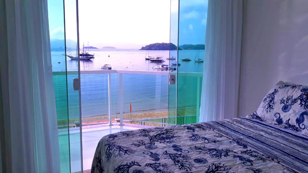 a bedroom with a large window with a view of the water at Apto Praia Grande - Angra dos Reis in Angra dos Reis
