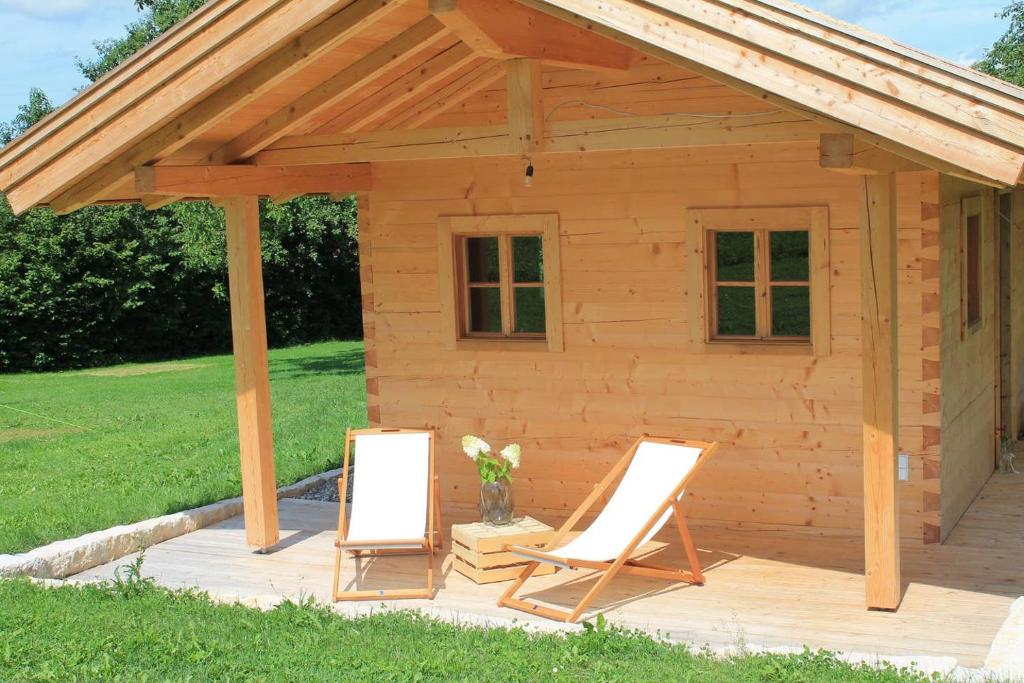 a wooden shed with two chairs on a deck at Holzchalet in Kirchanschöring