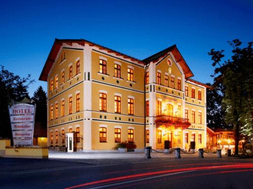 Un grand bâtiment est éclairé la nuit. dans l'établissement Hotel & Restaurant Waldschloss, à Passau