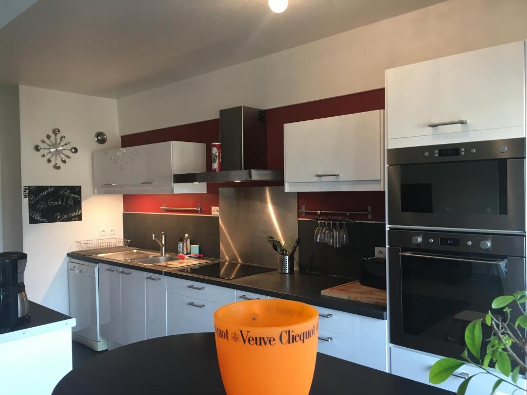 ランスにあるBedinReims "red bottle" 105m2 on one level, 4 bedrooms with double beds wifi free ideal 4 à 8 Adultes 2 bathrooms free parkingのキッチン(白いキャビネット、オレンジの椅子付)