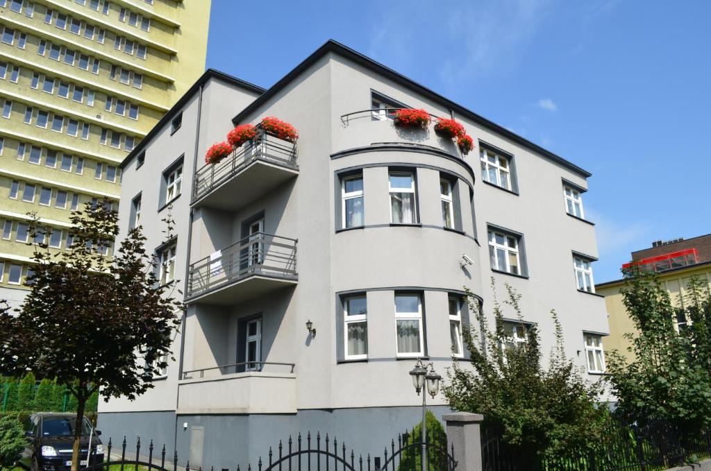 a white building with red flowers on it at Hostel Gwarek in Katowice