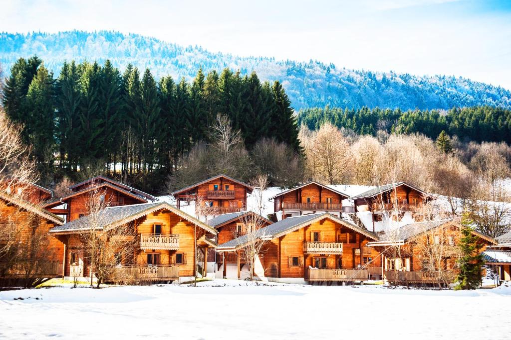 un groupe de maisons en bois dans la neige dans l'établissement Résidence Néméa Les Chalets du Bois de Champelle, à Morillon