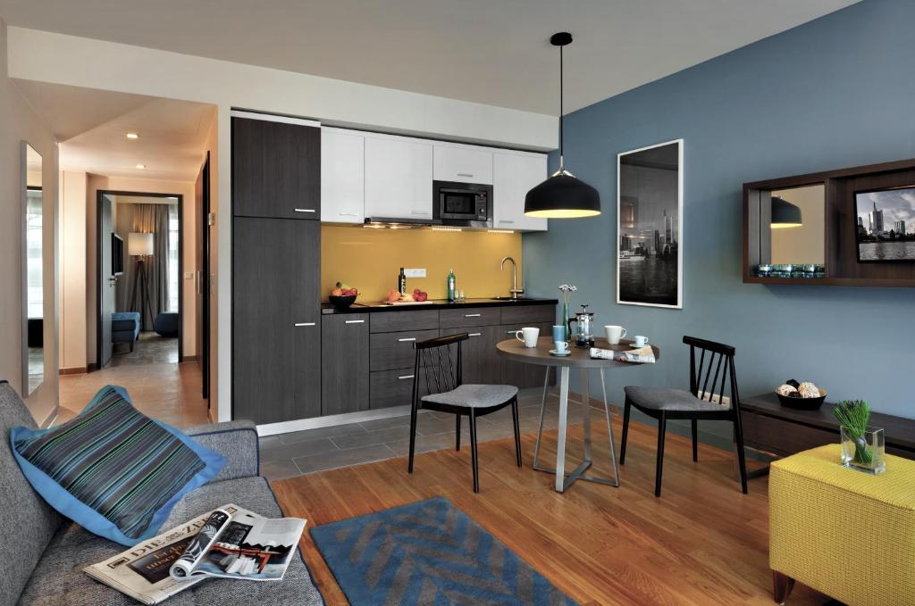 a living room and kitchen with a couch and a table at Citadines City Centre Frankfurt in Frankfurt