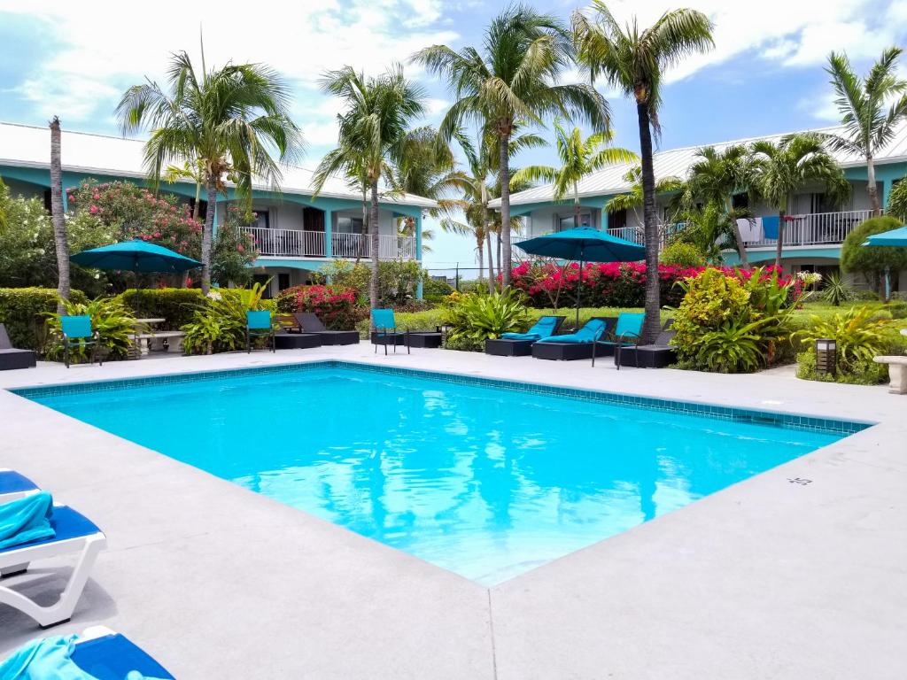 a swimming pool in front of a resort with palm trees at Island Club Turks & Grace Bay Place in Grace Bay