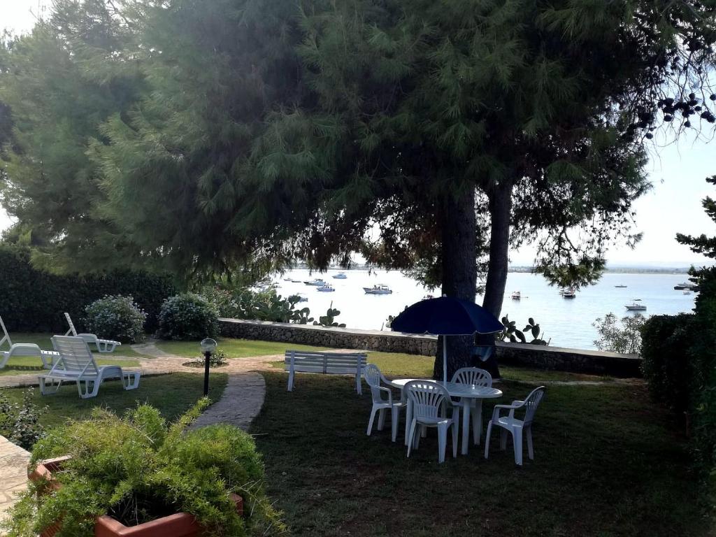 uma mesa e cadeiras debaixo de uma árvore junto à água em Villa Mazzei em Siracusa