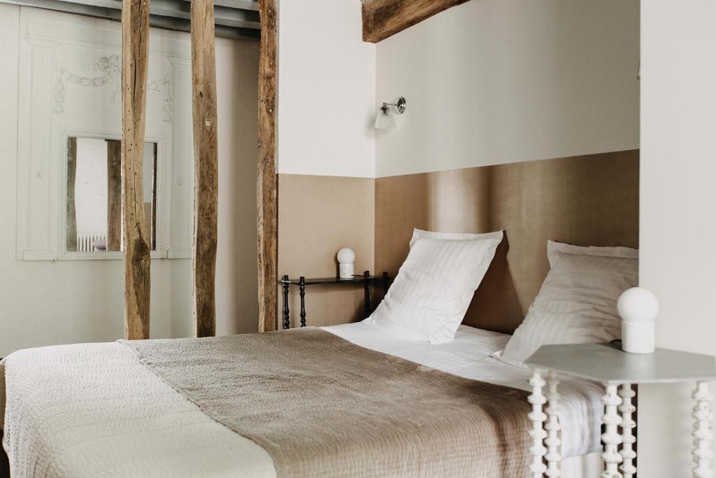 a bedroom with a large bed with a wooden headboard at La Dime de Giverny - Chambres d'hôtes in Giverny