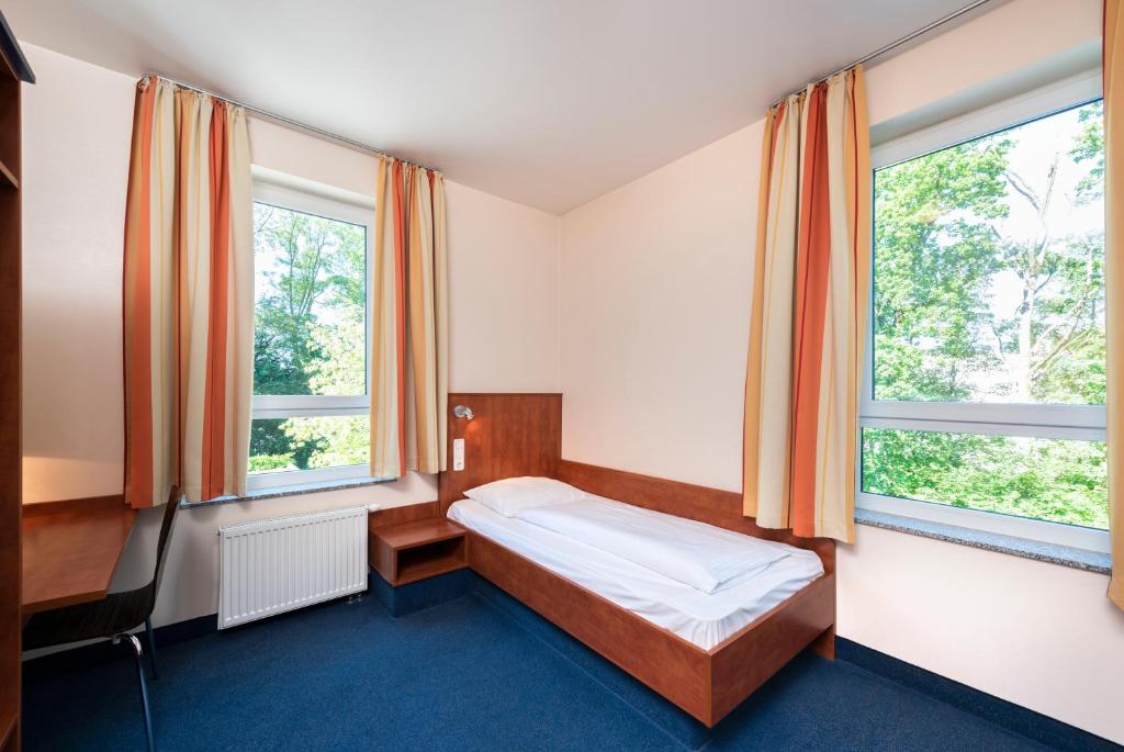 um pequeno quarto com uma cama e 2 janelas em smartMotel em Kempten