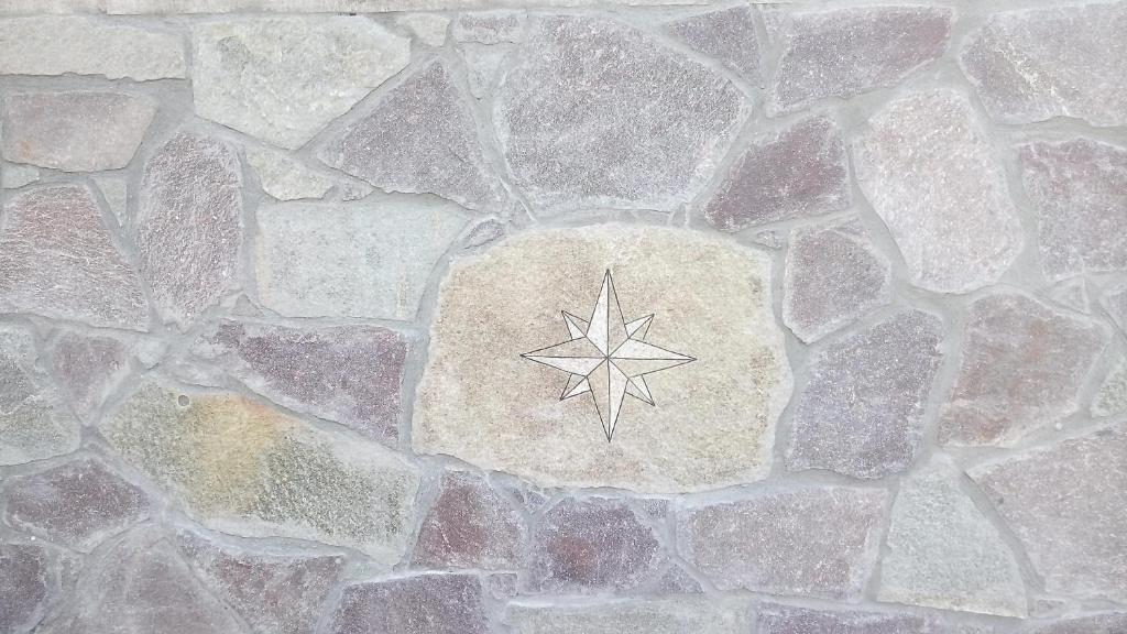 una pared de piedra con una estrella pintada en ella en B&B La Rosa Dei Venti Sardinya, en Sinnai