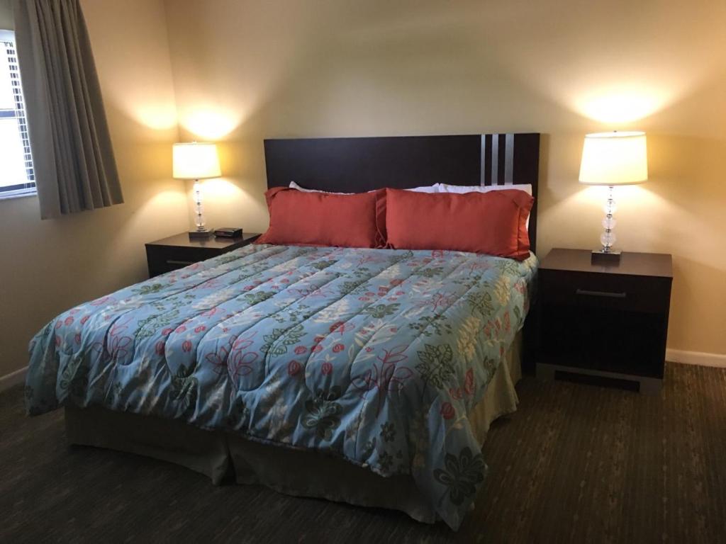 a bedroom with a bed with red pillows and two lamps at Surfsider Resort - A Timeshare Resort in Pompano Beach