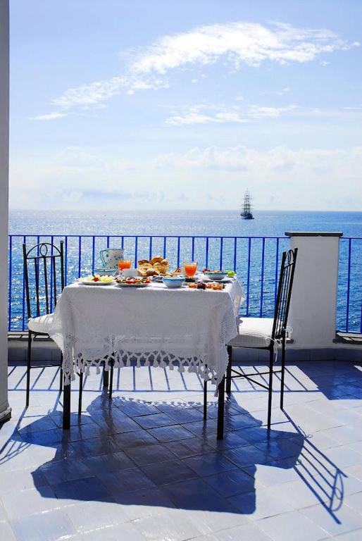 a table on a balcony with a view of the ocean at Hotel Palladio in Giardini Naxos
