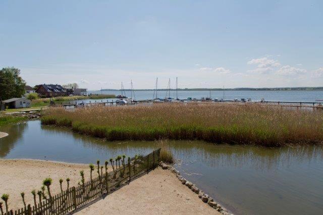 a body of water next to a beach with a fence at Traumblick Ferienwohnung in Sauzin