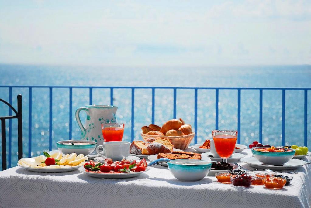a table with food on it with a view of the ocean at Hotel Palladio in Giardini Naxos
