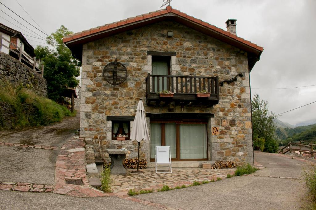 ein kleines Steinhaus mit Balkon und Sonnenschirm in der Unterkunft llar de Cosme in Caso