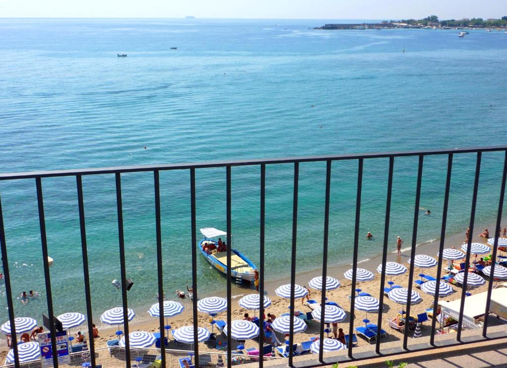 a beach with a bunch of umbrellas and people on the beach at Hotel Palladio in Giardini Naxos