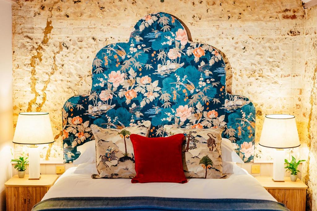 a bed with a blue and white headboard with a red pillow at The Grosvenor Stockbridge in Stockbridge