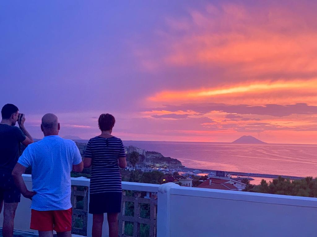a group of people standing on a balcony watching the sunset at Villino Eleonora in Parghelia