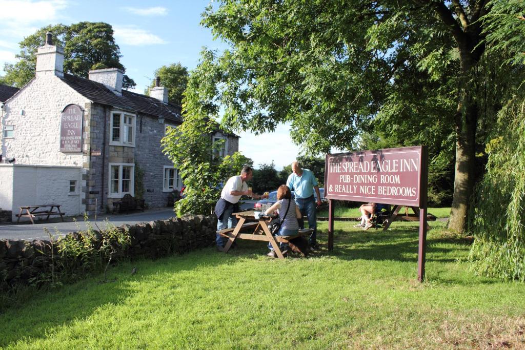 um grupo de pessoas sentadas numa mesa de piquenique em frente a uma placa em The Spread Eagle em Clitheroe