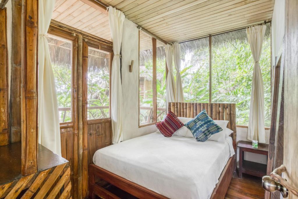 a bedroom with a bed in a room with windows at Selina Amazon Tena in Tena