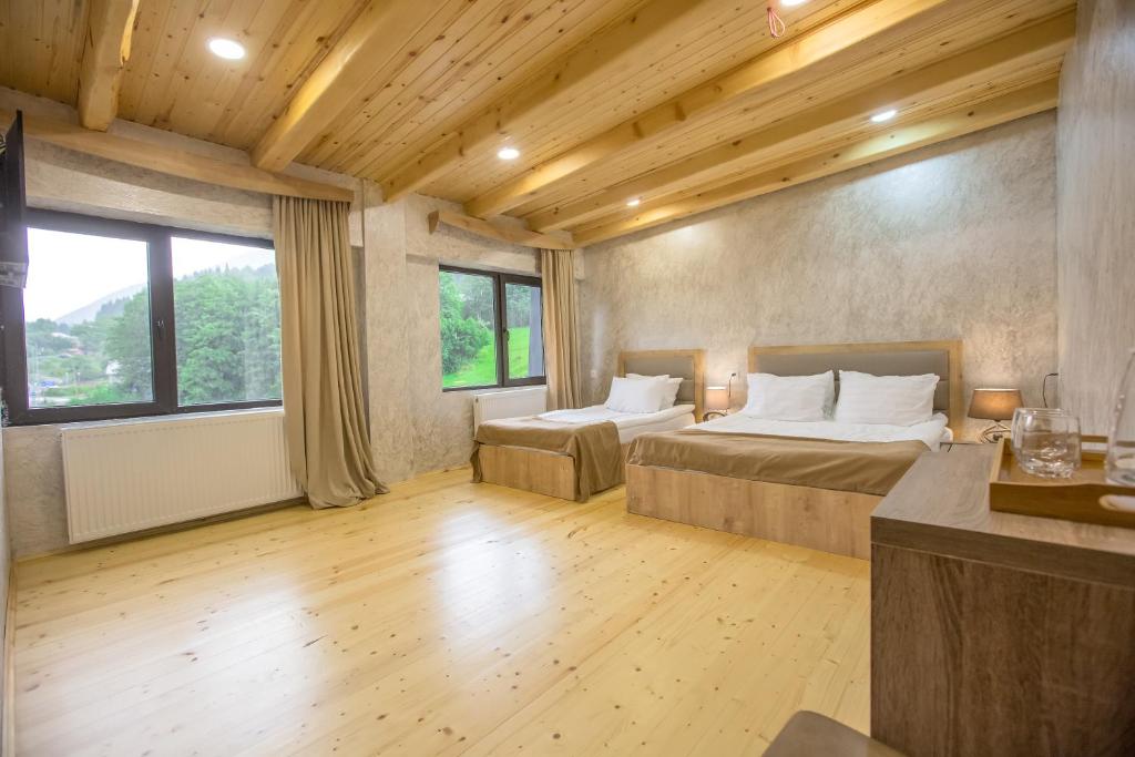 a bedroom with two beds and a large window at Suntower Hotel in Mestia