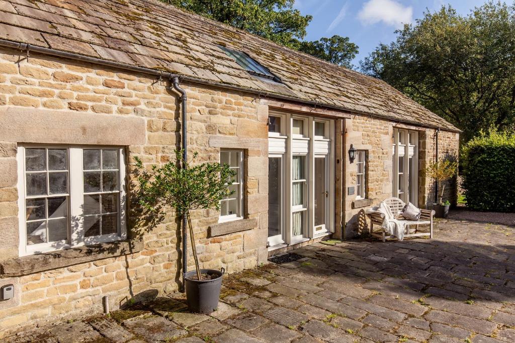 a brick house with a potted tree in front of it at The Coach House Holiday Home in Stoney Middleton