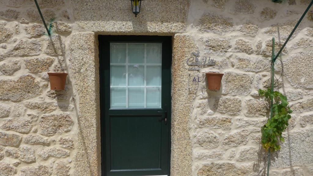 Relva的住宿－Casas da Villa - Monsanto - Oliveira e Videira，石头建筑上一扇带窗户的绿色门