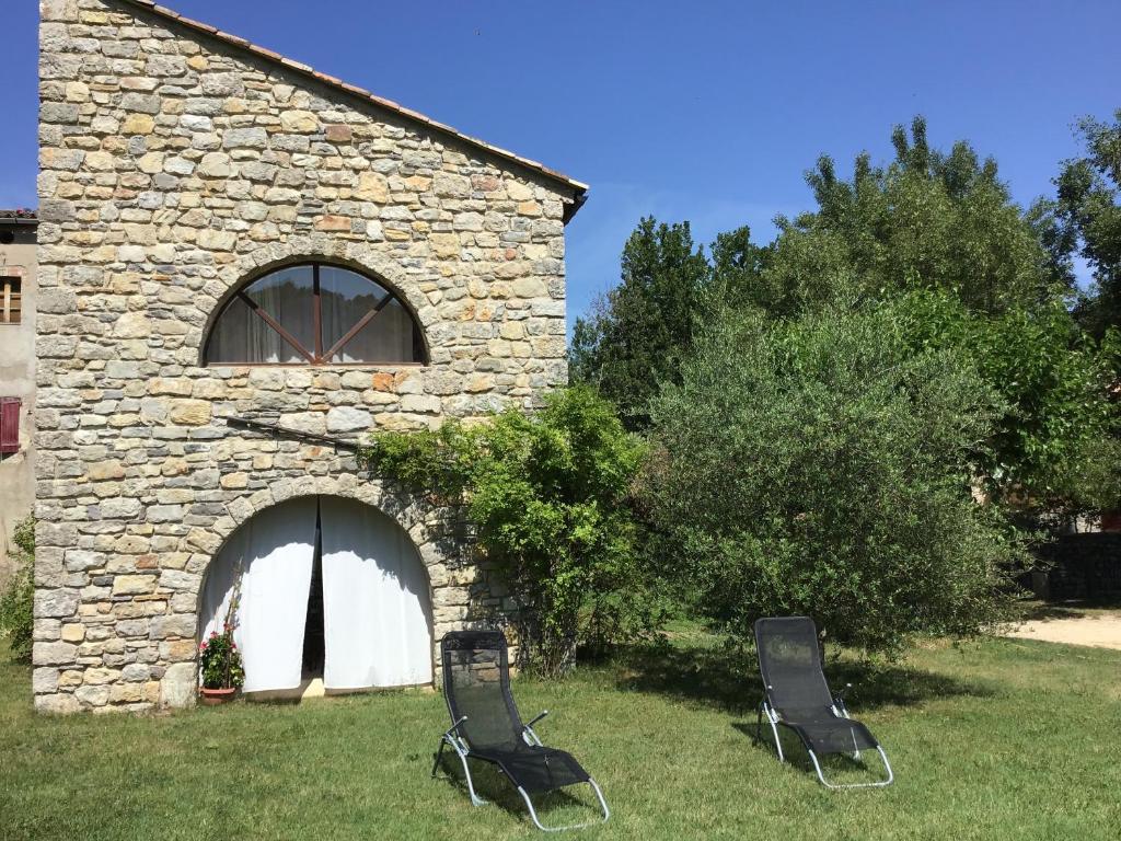 two chairs sitting in the grass in front of a building at Maison de vacances sud Ardèche in Berrias Et Casteljau