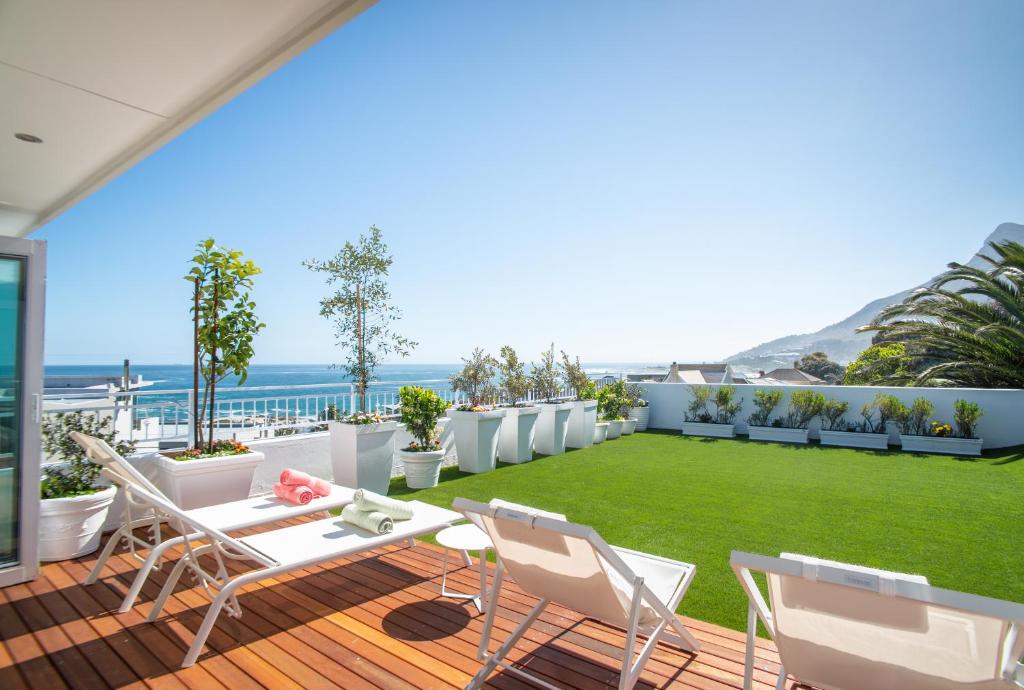 a patio with a lawn and chairs and the ocean at Funkey Villas Cape Town in Cape Town