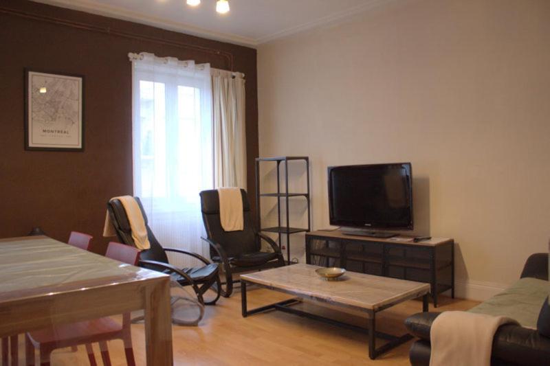 uma sala de estar com uma televisão de ecrã plano e cadeiras em Le MONTREAL F3 (2 chambres) Centre Ville/ GareTGV em Mulhouse