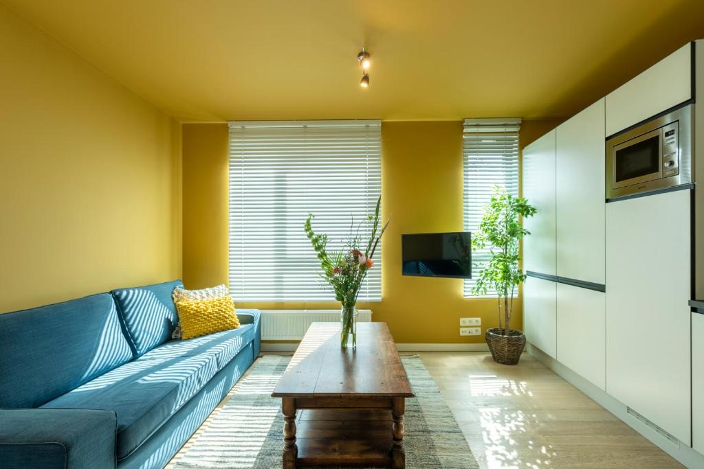 un soggiorno con un divano blu e un tavolino da caffè di SHWAY - The India Yellow Studio ad Anversa