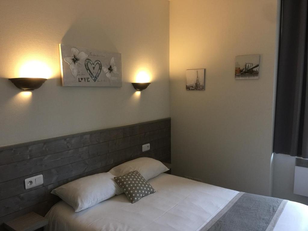 a bedroom with a bed with two lights on the wall at Hotel TGV in Quimper