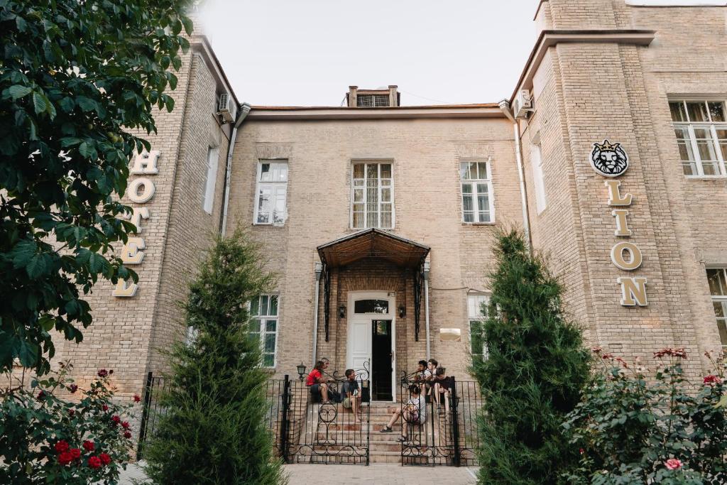 un grupo de personas sentadas frente a un edificio en Lion B&B, en Samarkand