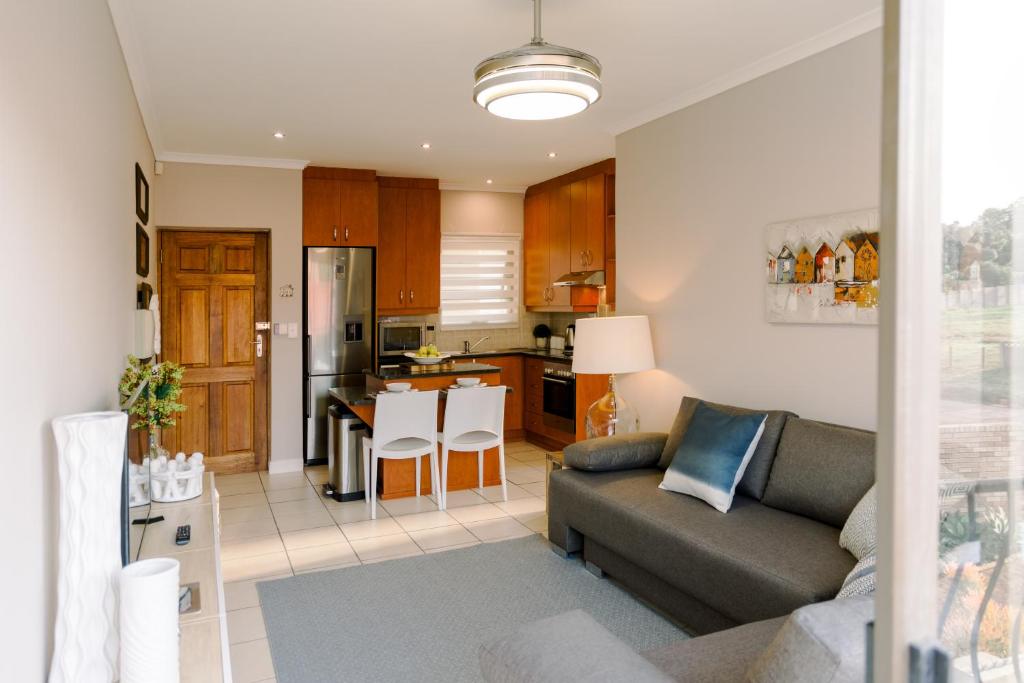 a living room with a couch and a kitchen at Serenity on Oribi in Jeffreys Bay