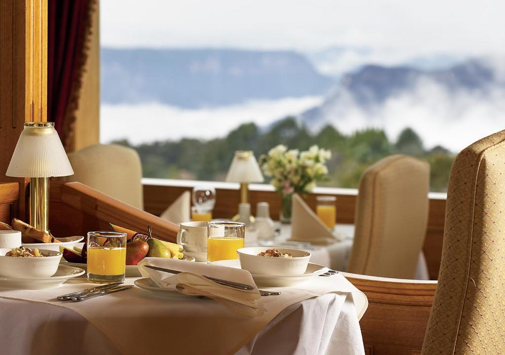 a table with food and drinks and a view of a mountain at Mountain Heritage Hotel in Katoomba