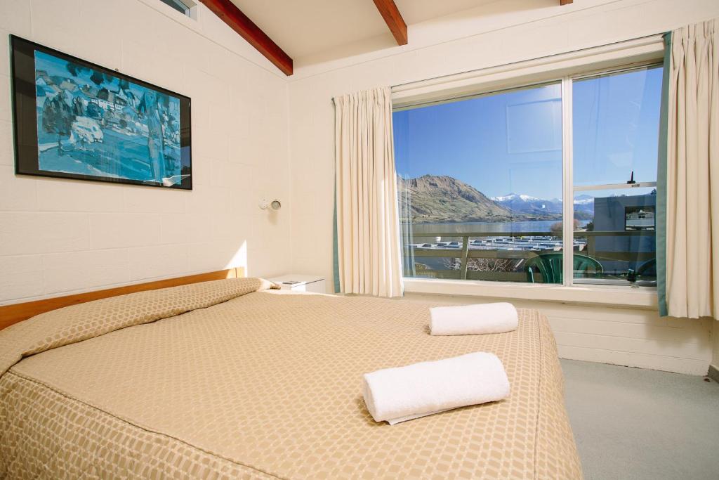 sypialnia z łóżkiem i dużym oknem w obiekcie Panorama Court w mieście Wanaka