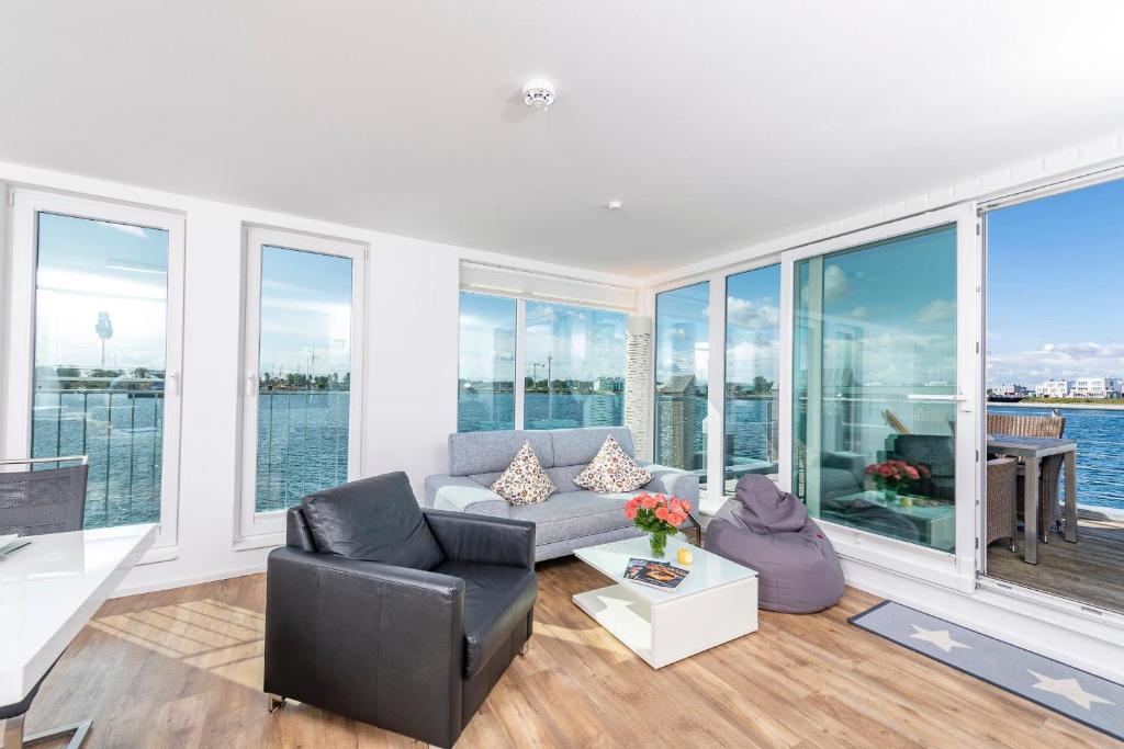 a living room with a couch and chairs and windows at Schwimmendes Haus Waterfront in Olpenitz