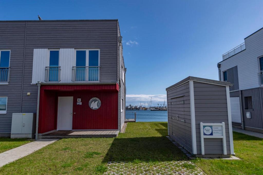 a house with a red door next to a building at Strandnest in Olpenitz