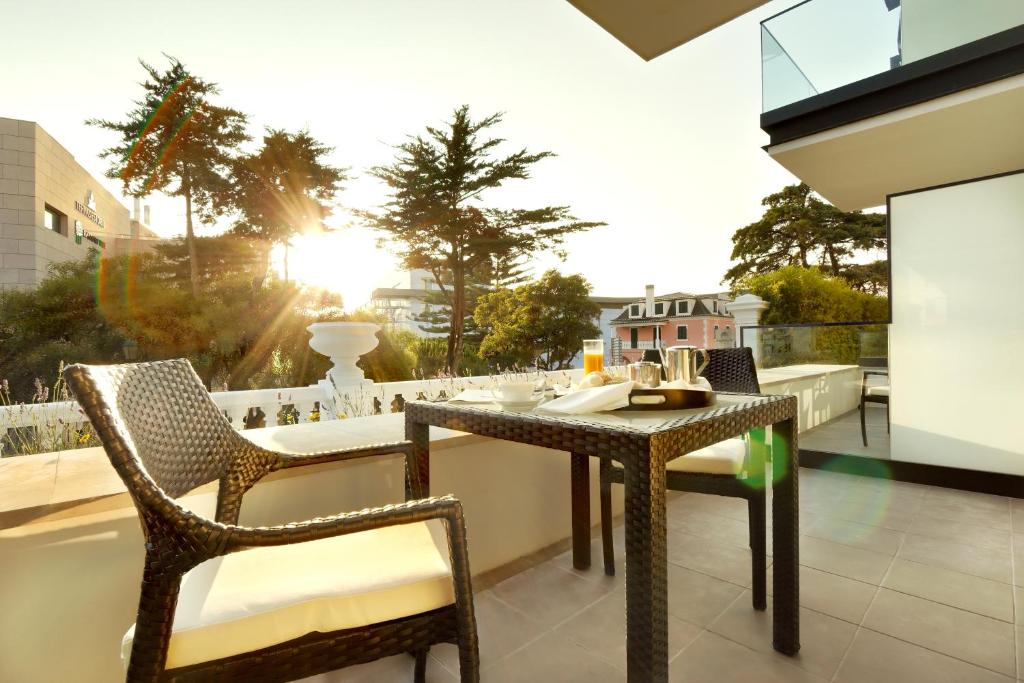 a table and two chairs on a balcony with the sunset at Hotel Inglaterra - Charme & Boutique in Estoril