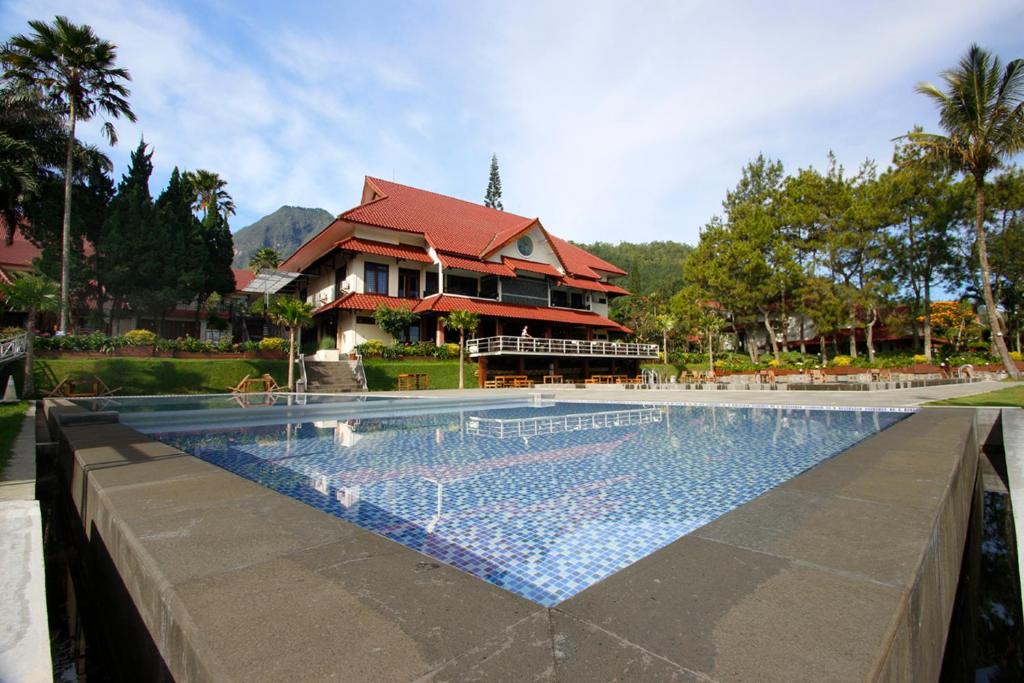 a house with a swimming pool in front of a house at Kusuma Agrowisata Resort & Convention in Batu