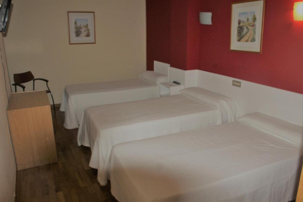 Habitación con 2 camas y pared roja. en Hotel Fuente La Plata, en Oviedo
