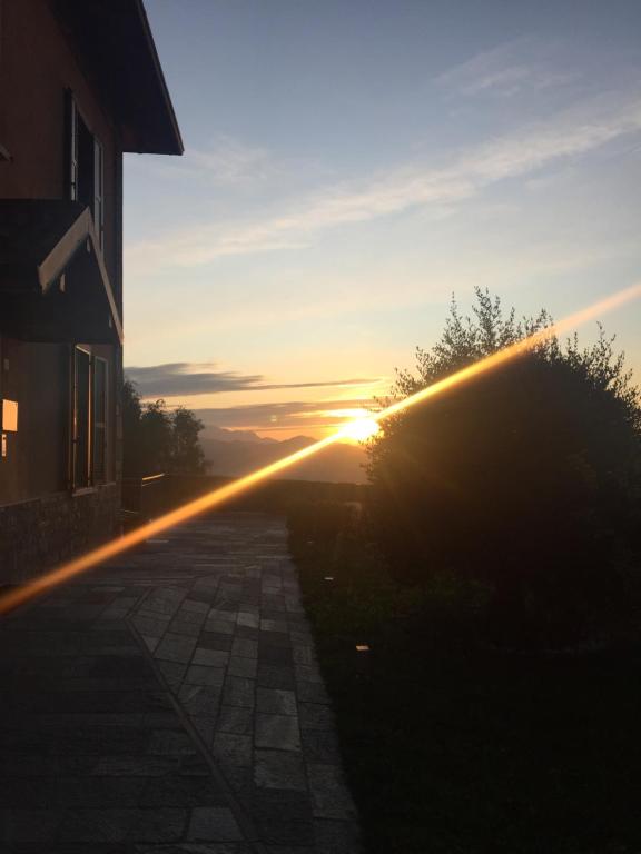 a sunset with the sun setting behind a building at Residence La Canonica in Costa Valle Imagna
