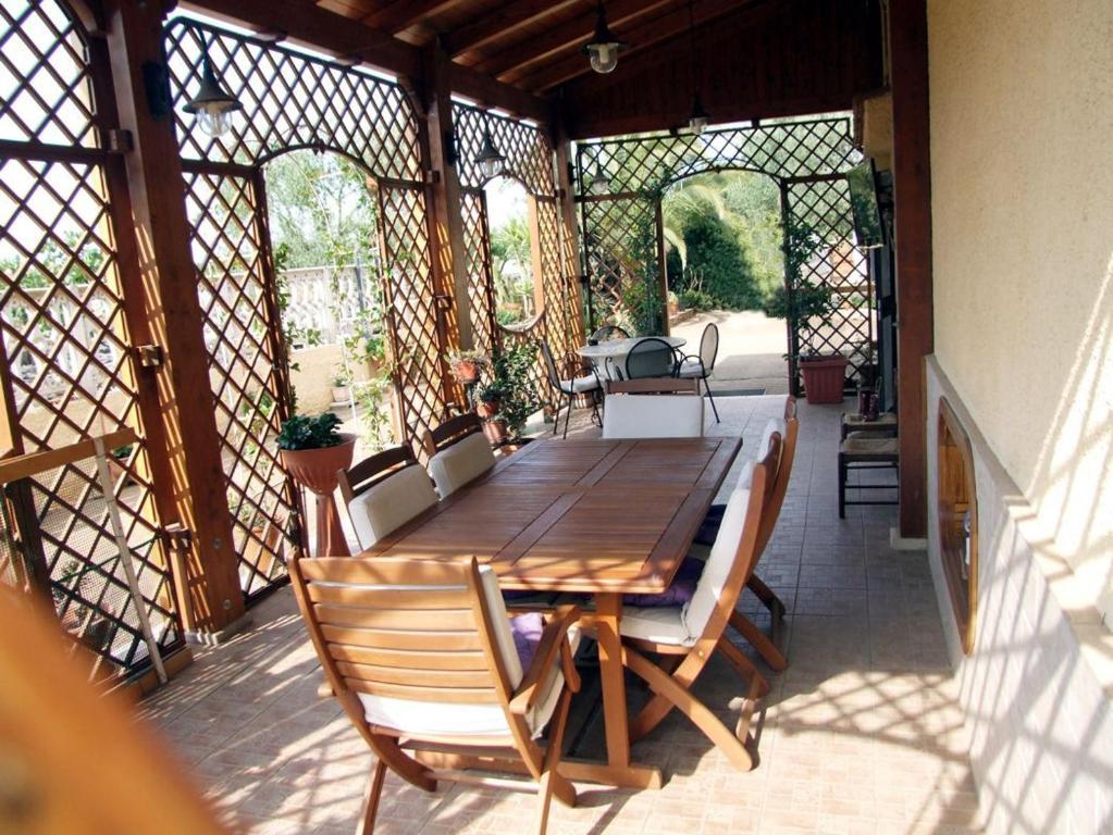 - une table et des chaises en bois sur une terrasse couverte avec moustiquaire dans l'établissement Villa Franca B&B, à Turi