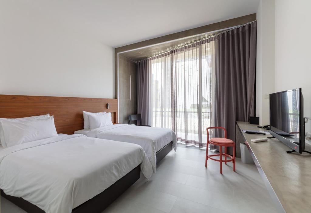 a hotel room with two beds and a flat screen tv at Reno hotel in Bangkok