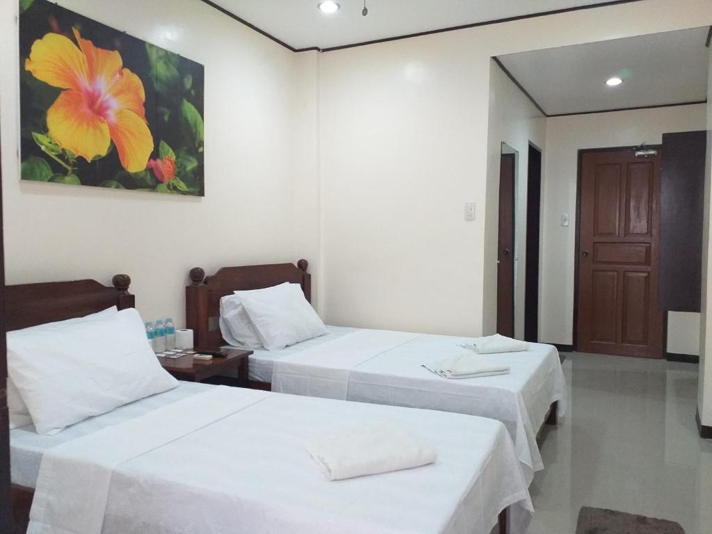 una habitación de hotel con 2 camas y un cuadro en la pared en Devayn's Inn en El Nido