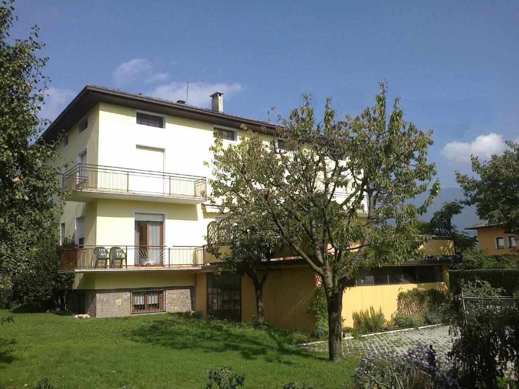 una grande casa bianca con un albero di fronte di Casa Ferrari Monica CIPAT 22032 a Calceranica al Lago